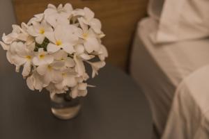 a vase filled with white flowers sitting next to a bed at Pousada Corveta in Fernando de Noronha