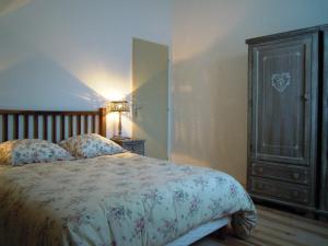 a bedroom with a bed with a wooden headboard and a cabinet at LES MARMOTTES in Gez