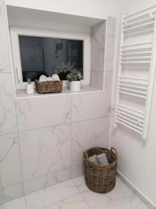 a white bathroom with a window and a basket at Apartment Mario in Ptuj