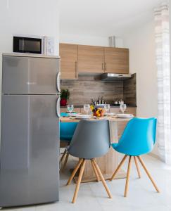 a kitchen with a refrigerator and a table with blue chairs at Apartmani Mabele in Pag