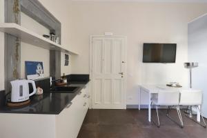 a kitchen with a sink and a table with white chairs at Apt. Perla - Pauline Suites, Palazzo Borghese in Florence