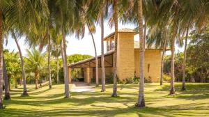 a building with palm trees in front of it at Refúgios Parajuru - Villa Cristiano in Parajuru