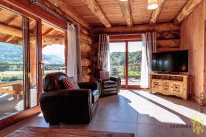 a living room with two chairs and a flat screen tv at Chalets de Fougerousse in Chambon-sur-Lac