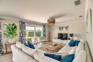 a living room with a white couch and a tv at Lavish Vero Beach Escape with Pool, Patio and Dock! in Vero Beach