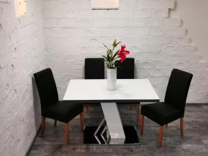 a white table with a vase with a red flower on it at Luxury Basement in the surrounding of Budapest in Mogyoród