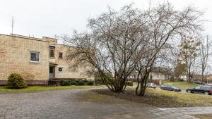 ein Baum vor einem Gebäude mit geparkten Autos in der Unterkunft Abariaus Apartamentai in Druskininkai