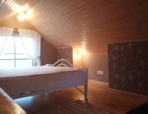 a bed in a room with a wooden ceiling at Kelluka Holiday House in Pärispea