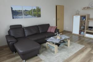 sala de estar con sofá negro y mesa en Ferienwohnung Unica im Lahntal, en Villmar