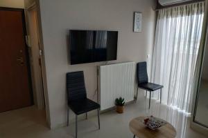 uma sala de estar com duas cadeiras e uma televisão na parede em Psychiko's View em Atenas