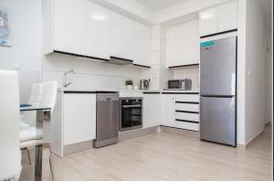 une cuisine avec des armoires blanches et des appareils en acier inoxydable dans l'établissement 003 Apartament Puerto Romano, à La Mata