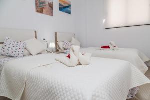 two white beds with stuffed animals on top of them at Apartament Puerto Romano, La Mata, close to the beach plus parking space in the underground garage in La Mata +20 photos