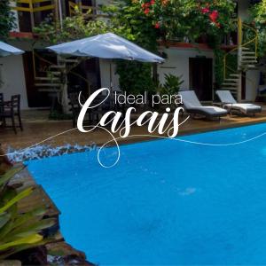 a blue swimming pool with an umbrella next to a house at Pousada Casa de Maria in Prado