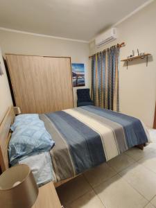 een slaapkamer met een groot bed en een blauwe deken bij Doms Apartment in Tarxien