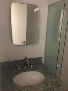 ein Bad mit einem Waschbecken und einem Spiegel in der Unterkunft APTO CHURRASQUEIRA, Capitania Varam, Pitangueiras, piscina, 100 m da praia, 2 dormitórios, 2 vagas de garagem in Guarujá