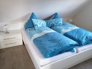 グレートジールにあるFerienwohnung Hafenliebe-Greetsielのベッド(青いシーツ、枕付)