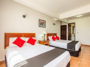 2 camas en una habitación de hotel con almohadas rojas en Hotel Santa Lucia, en Oaxaca City