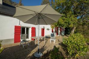 een patio met een tafel en stoelen en een parasol bij Comfortable farm house Petit Barzun, in the Parc National Pyrenees in Barèges