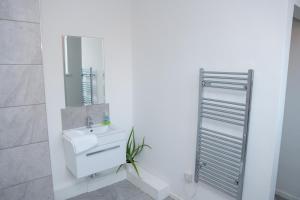 ein weißes Badezimmer mit einem Waschbecken und einem Spiegel in der Unterkunft Luke Stays - Front Street in Newcastle upon Tyne
