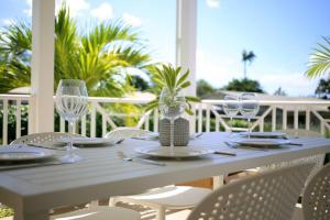 a white table with chairs and glasses on a porch at Sea Glass Villa - Spacious 1 Bed, 2 Bath on West Coast in Saint James