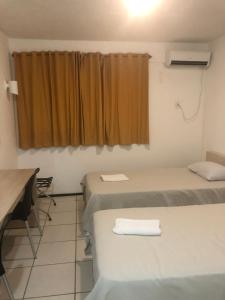 a room with three beds and a table and a window at Melo Hospedagem - Flat Bellagio in São Luís