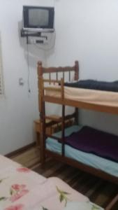 Zimmer mit 2 Etagenbetten und einem TV in der Unterkunft Pousada Alquidora in São Thomé das Letras