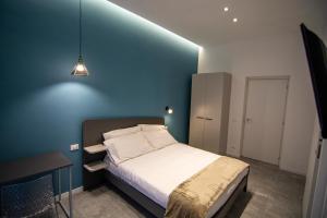 een slaapkamer met een bed met een blauwe muur bij Dadà House in Catania