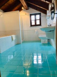 y baño con suelo de baldosa azul y lavamanos. en Viaggio della Vita B&B, en Fontanile
