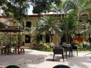 un patio con mesas, sillas y palmeras en La Sirena Playa Jacó, en Jacó