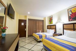 pokój hotelowy z 2 łóżkami i telewizorem w obiekcie Hotel Ambassador Mérida w mieście Mérida