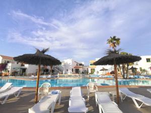 a group of chairs and umbrellas next to a swimming pool at Puerta del Sol casa Lily Caleta de Fuste in Caleta De Fuste