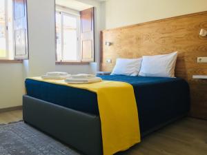 um quarto com uma cama com lençóis azuis e amarelos em My Historic House 1 em Brangança
