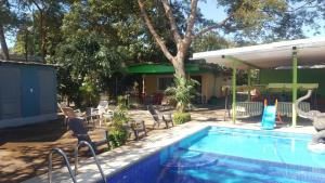 una piscina con sillas, una mesa y una casa en Hotel La Arboleda, en Managua
