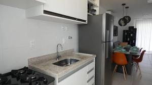 cocina con fregadero y nevera de acero inoxidable en Apto Guarajuba Praia Condomínio Porto Smeralda, en Guarajuba