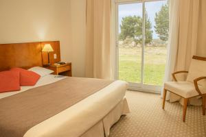 a hotel room with a bed and a window at Elegance Hotel Tandil in Tandil