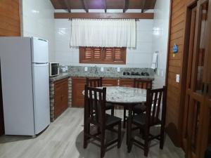 uma cozinha com uma mesa e cadeiras e um frigorífico em Casa Aconchegante Praia do Rosa Ibiraquera SC em Imbituba