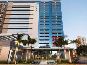 a tall building with palm trees in front of it at ibis budget Campinas Aquidaban in Campinas