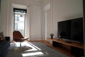 a living room with a television and a chair at Flora Baixa Apartments in Lisbon