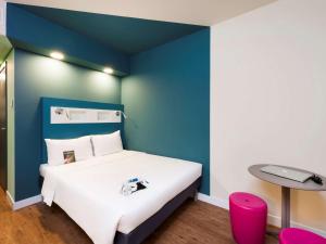 Un dormitorio con una cama con una pared de acento azul en ibis budget Navegantes Itajai en Itajaí