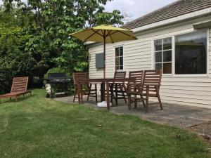 eine Terrasse mit Tisch und Stühlen und einem Sonnenschirm in der Unterkunft Ngapuna Cottage in Christchurch