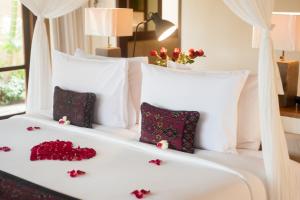 a white bed with red flowers on it at Komaneka at Tanggayuda Ubud in Ubud