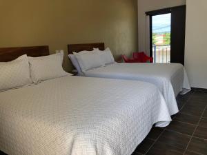 two beds sitting in a room with a window at Hotel Del Mar in Barra de Navidad