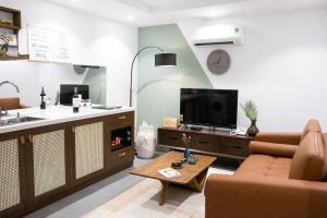 a living room with a couch and a tv and a table at Quang Vinh Apartment and Hotel Hoi An in Hoi An