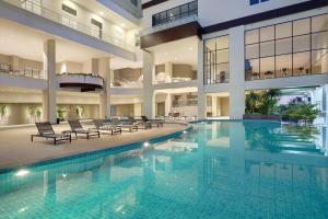 a large swimming pool in a building with chairs at Mercure Bengkulu in Bengkulu