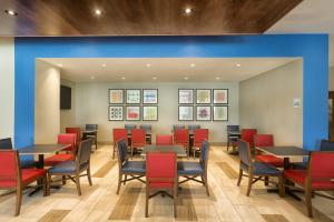 a dining room with tables and red chairs at Holiday Inn Express & Suites S Lake Buena Vista by IHG in Kissimmee