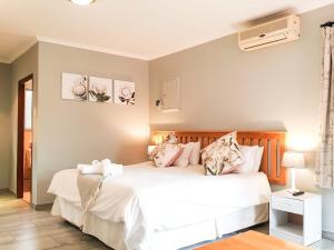 um quarto com uma cama com lençóis brancos e almofadas em Thyme Inn on Greenway em White River