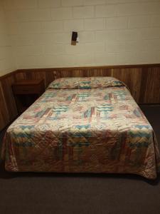 a bed in a room with a quilt on it at Opal Inn Hotel, Motel, Caravan Park in Coober Pedy