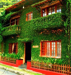 budynek pokryty zielonym bluszczem z czerwonymi oknami w obiekcie Raintree Lodge w mieście Koczin