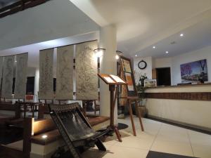 a salon with a chair and a table and a clock at Plumeria Hotel in Antsirabe