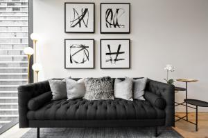 a living room with a black couch and framed pictures at Luxuria Apartments - Collins House in Melbourne