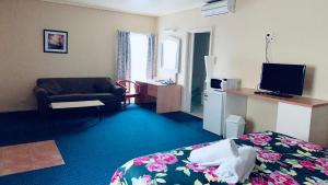a hotel room with a bedroom with a bed and a television at City East Motel in Melbourne